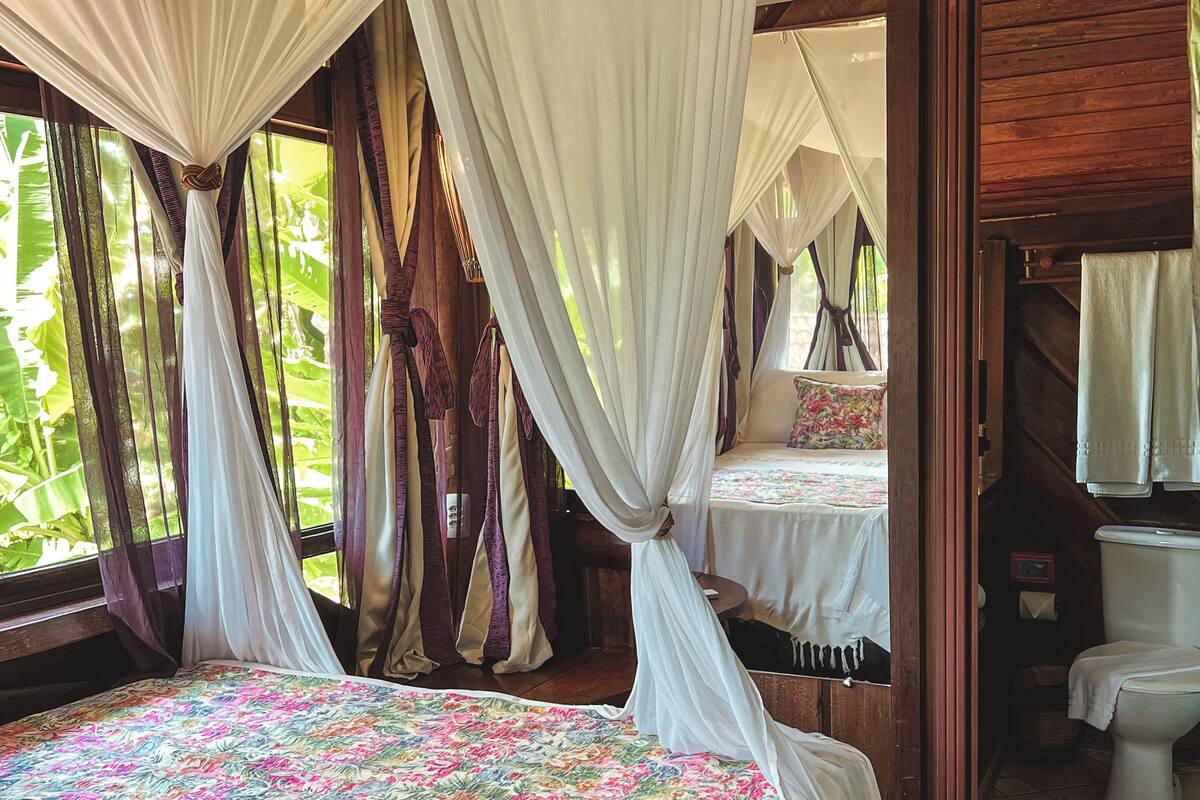 A bedroom with a bed, curtains, and a view of the outdoors.