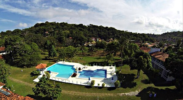 A large swimming pool surrounded by lush greenery and a hilly landscape.