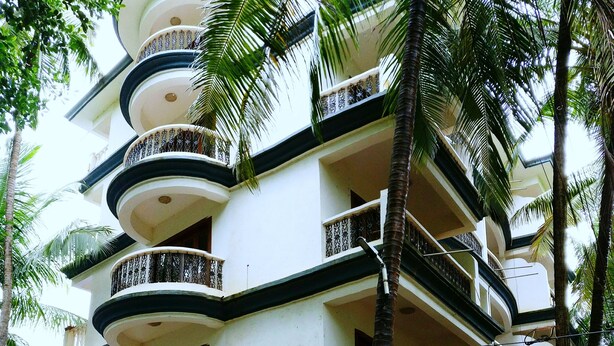 Un immeuble à plusieurs étages doté de balcons, entouré de palmiers.
