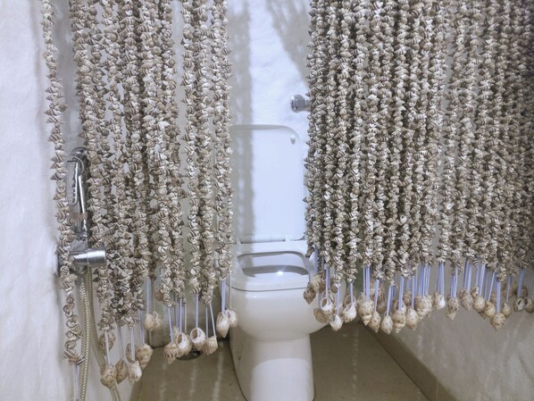 Des toilettes avec un abattant en porcelaine blanche et une poignée de chasse d’eau chromée.