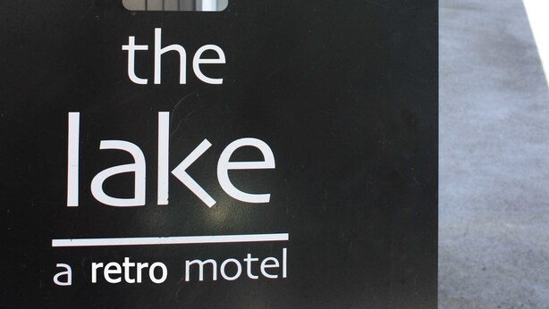 Et skilt for motellet 'The Lake' med et retro design, sort baggrund og hvid skrift.