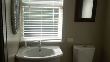 A bathroom with a white sink, a toilet, and a window with blinds.