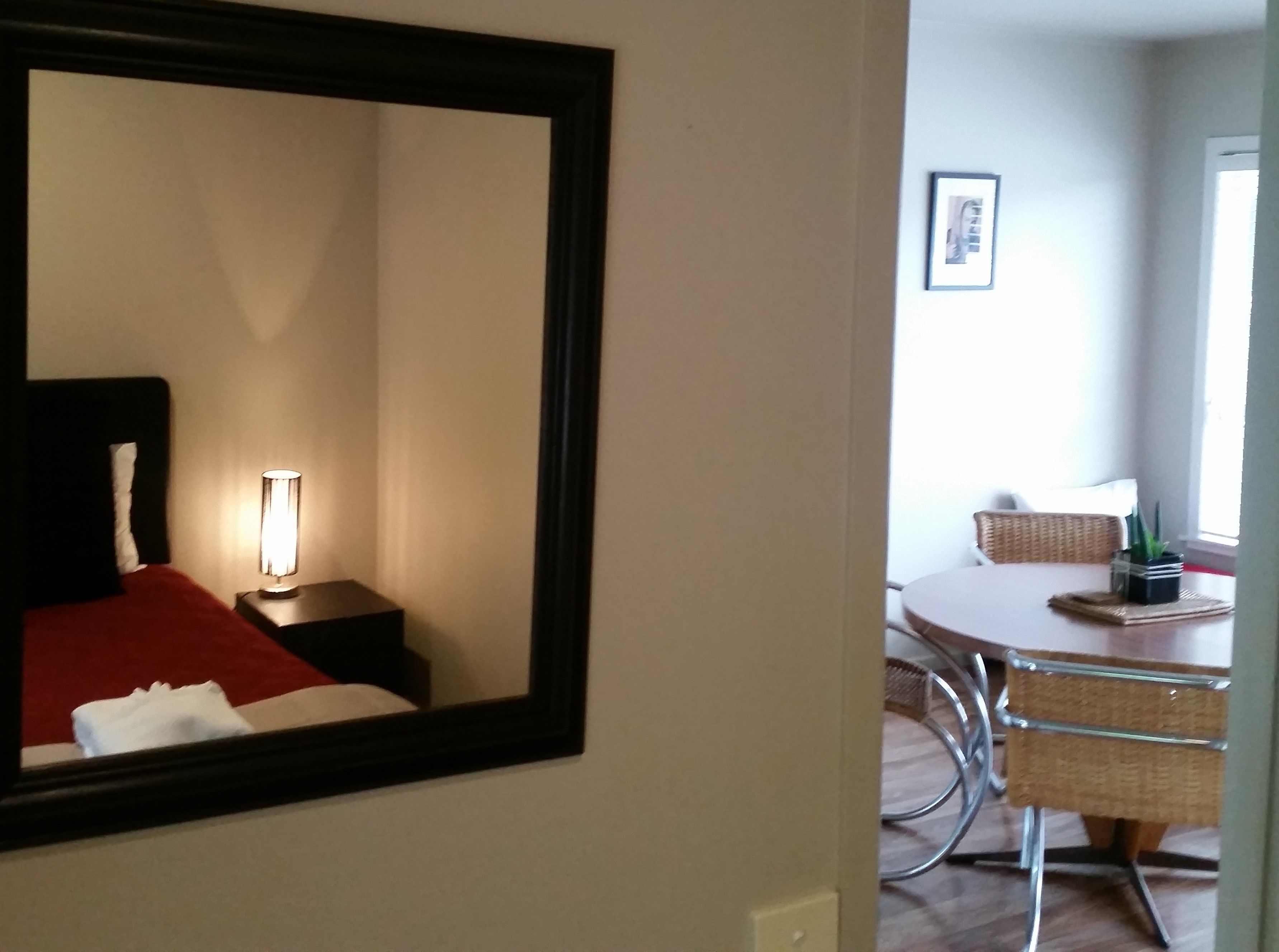 A hotel room with a bed, bedside lamp, and a dining area with a table and chairs.