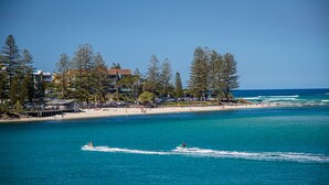 A coastal area with a beach, a pier, and a clear blue sky. - Tripcony Quays Apartments (Caloundra)
