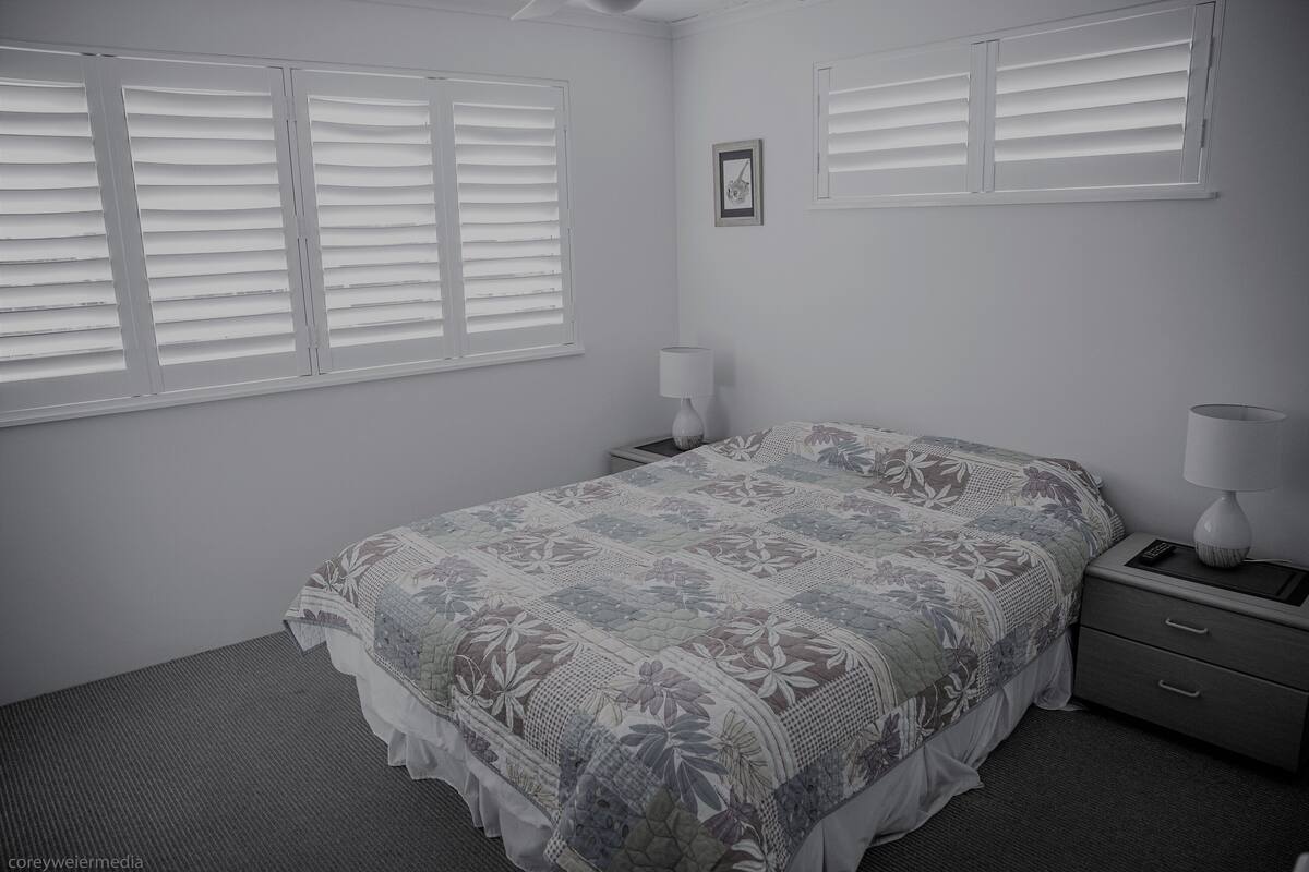 A bedroom with a bed, two bedside tables, a nightstand, and a wall-mounted picture.