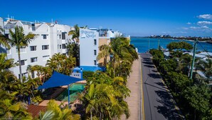 A hotel with a pool, palm trees, and a view of the ocean. - Tripcony Quays Apartments (Caloundra)