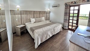 Een hotelkamer met een groot bed, nachtkastjes, een bureau en een balkon met uitzicht.