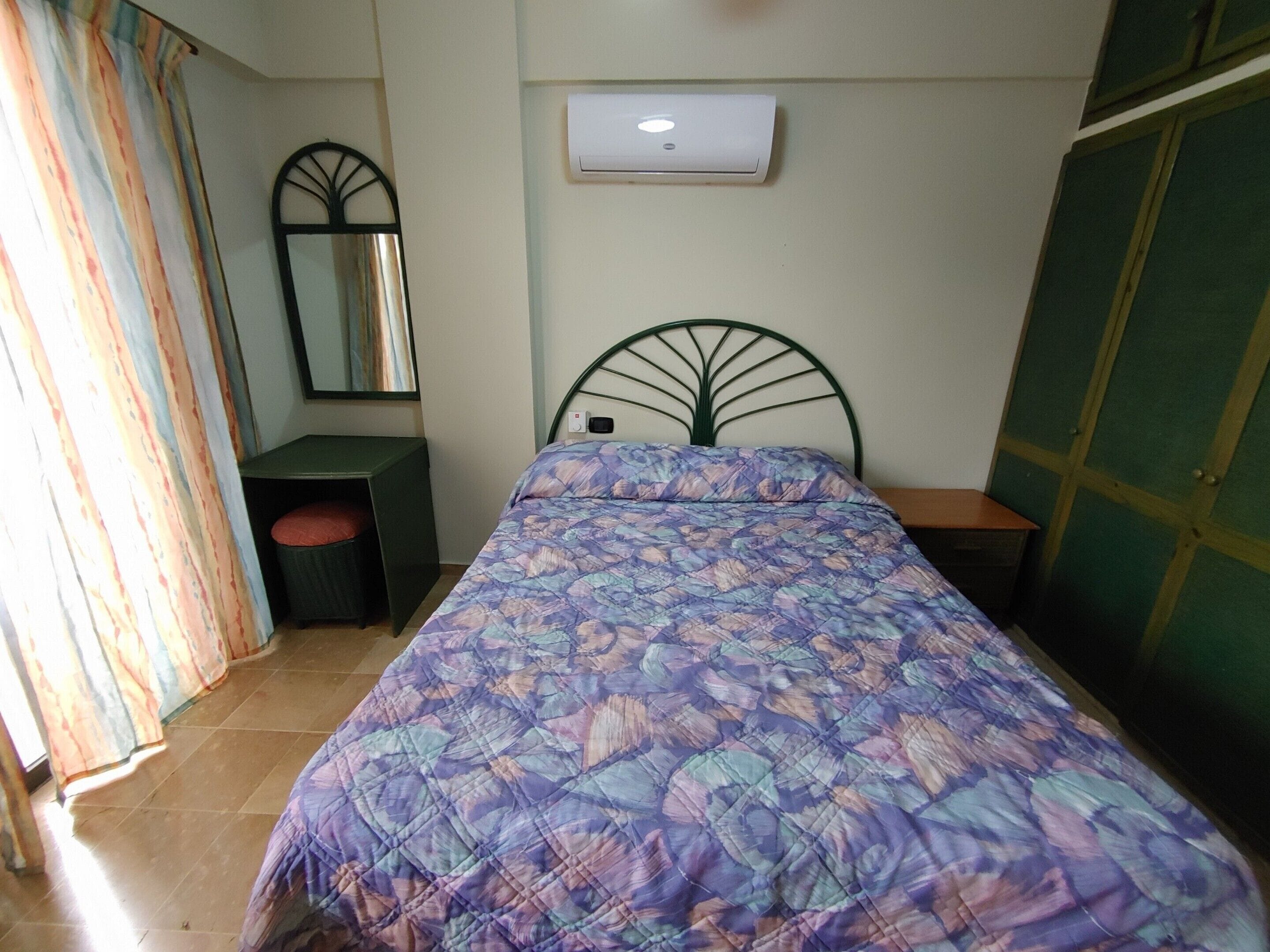 Un dormitorio con una cama, un aparador, un espejo y un equipo de aire acondicionado.