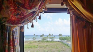 Ein Zimmer mit Blick auf einen Strand und Palmen.