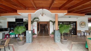 Eine großzügige Lobby mit Fliesenboden, Holzbalkendecke und Zimmerpflanzen.