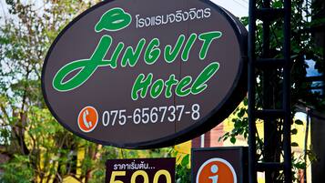 A sign for Jingjit Hotel with a contact number and a price tag.
