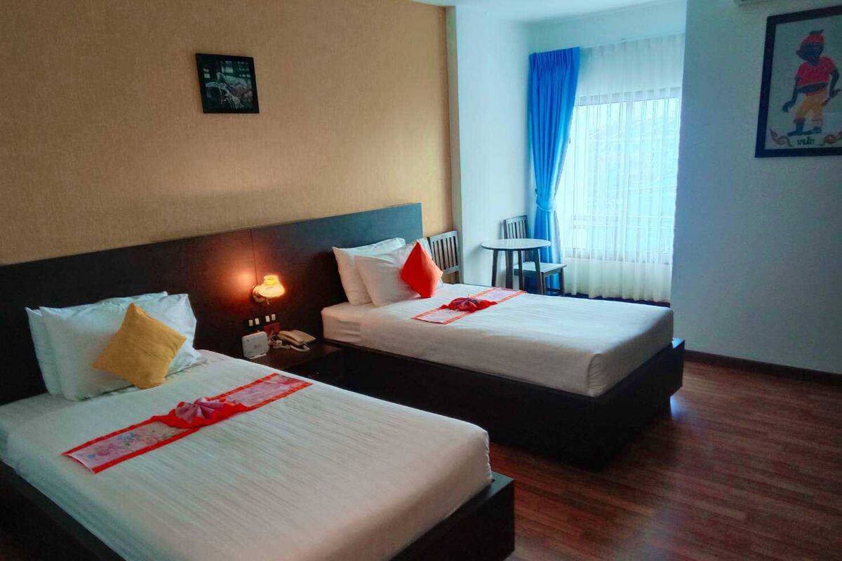A hotel room with two beds, a small table, and a chair.
