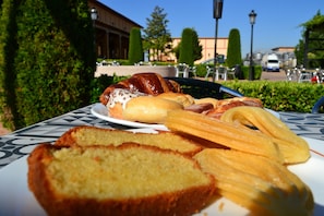A table with pastries and bread, a building, and a clear sky in the background. - Complejo Enoturístico Finca La Estacada (Tarancon)