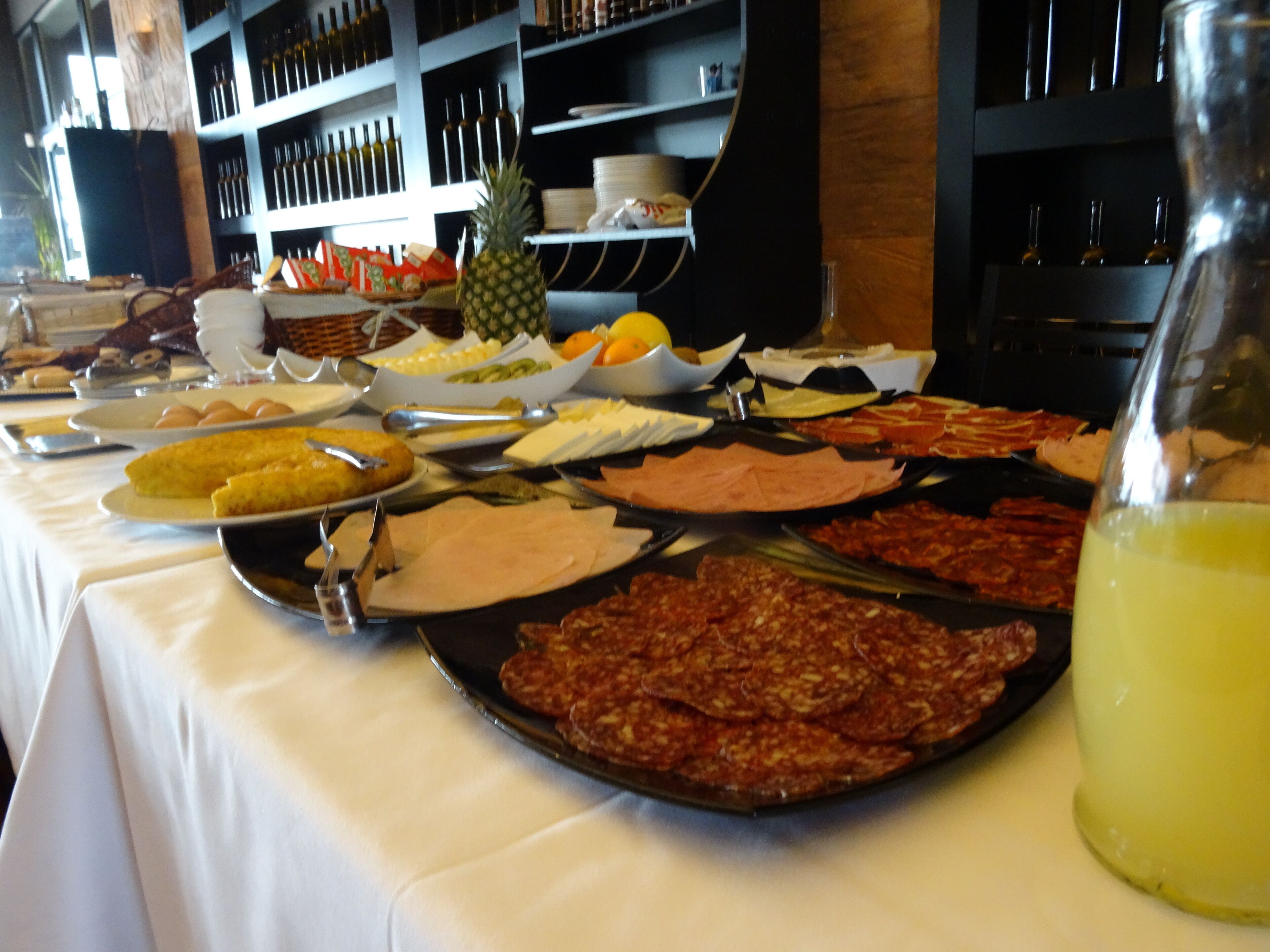 Una mesa de buffet con diversas opciones de comida y una botella de jugo.