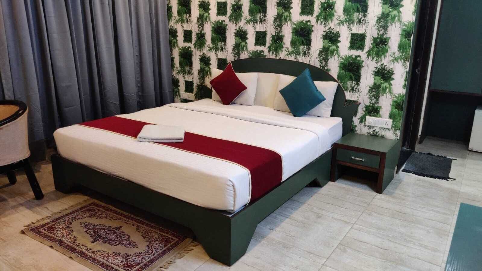 Una cama con una colcha roja y blanca, un cabecero de madera oscura y una mesita de noche pequeña con un cajón.
