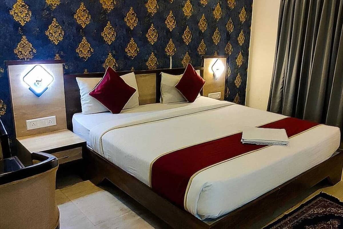 Una habitación de hotel con una cama grande, mesitas de noche, una lámpara y una cortina.