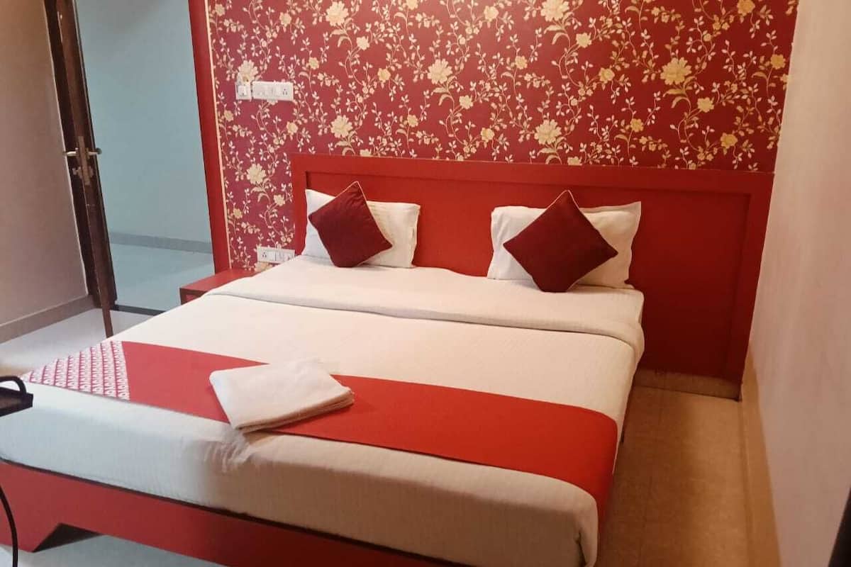 Una cama con cabecera roja, ropa de cama blanca y almohadas rojas.