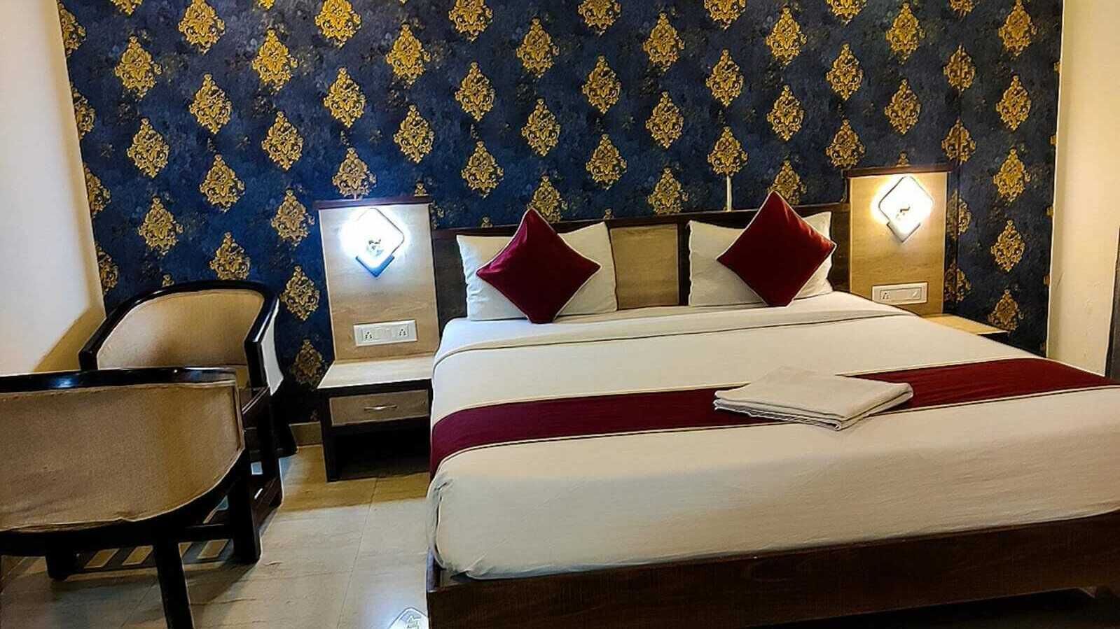 Une chambre d’hôtel avec un lit, deux tables de chevet, une chaise et un mur décoré d’un motif.