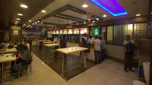 A restaurant with multiple dining tables and a counter where people are ordering food. - Royal Shades (Bengaluru)