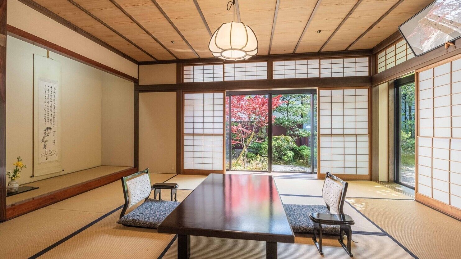 Una habitación japonesa tradicional con suelo de tatami, una mesa baja y puertas correderas shoji.