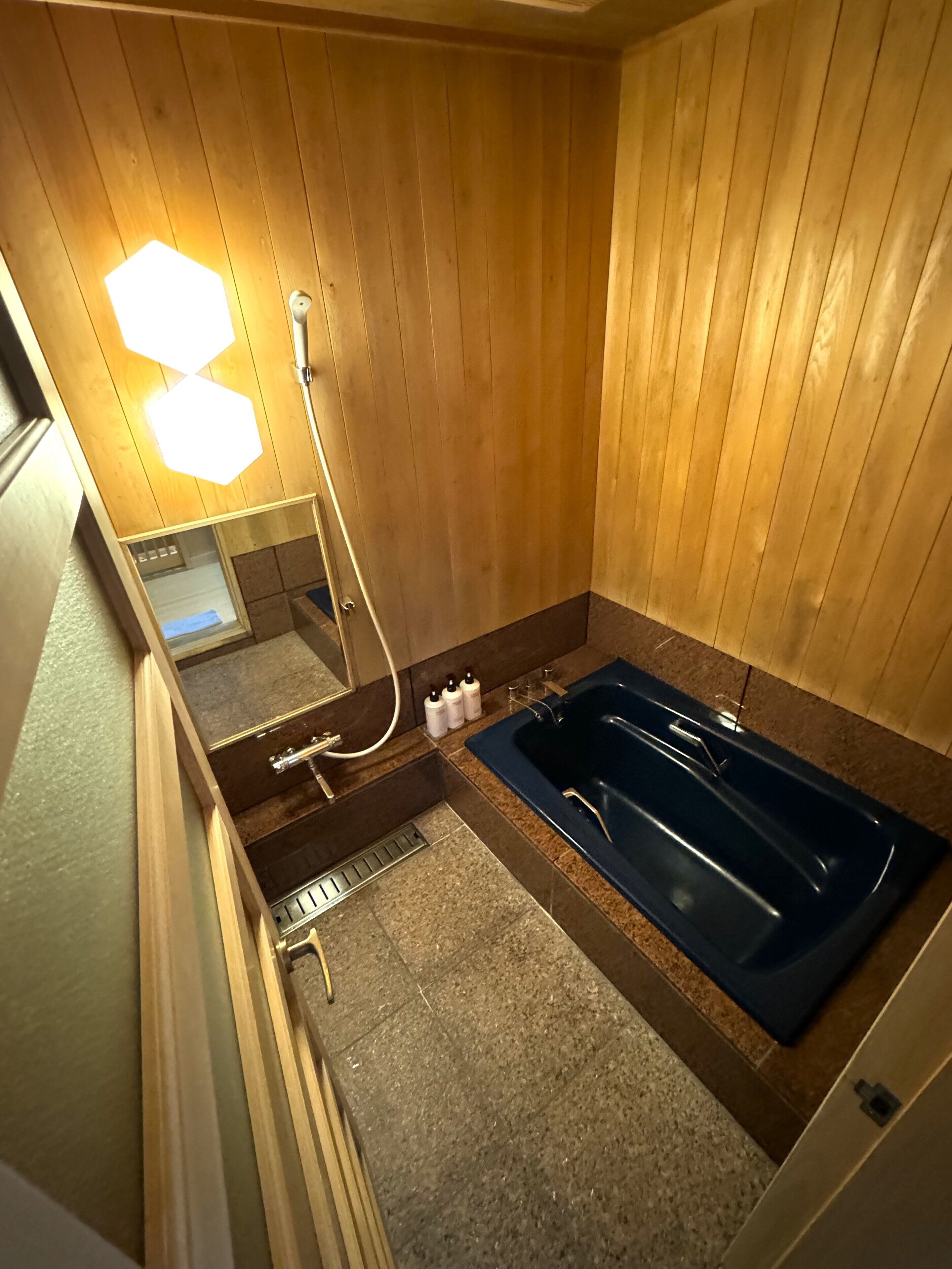 A wooden-paneled room with a bathtub, a mirror, and a shower.