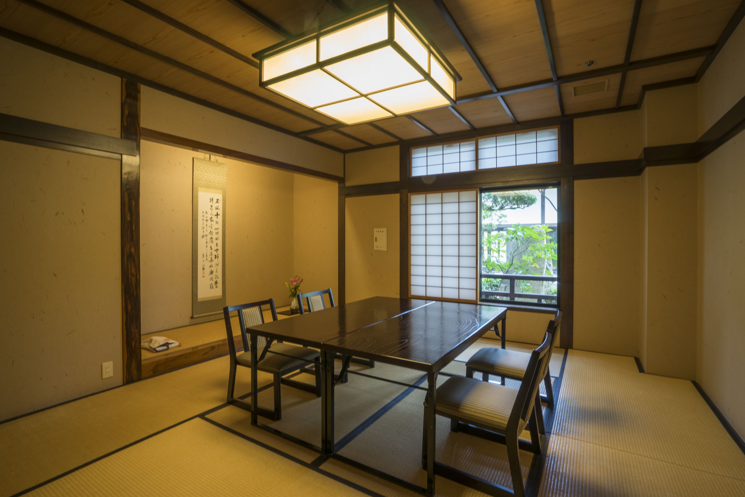 A traditional Japanese room with tatami flooring, a low table, and sliding doors.