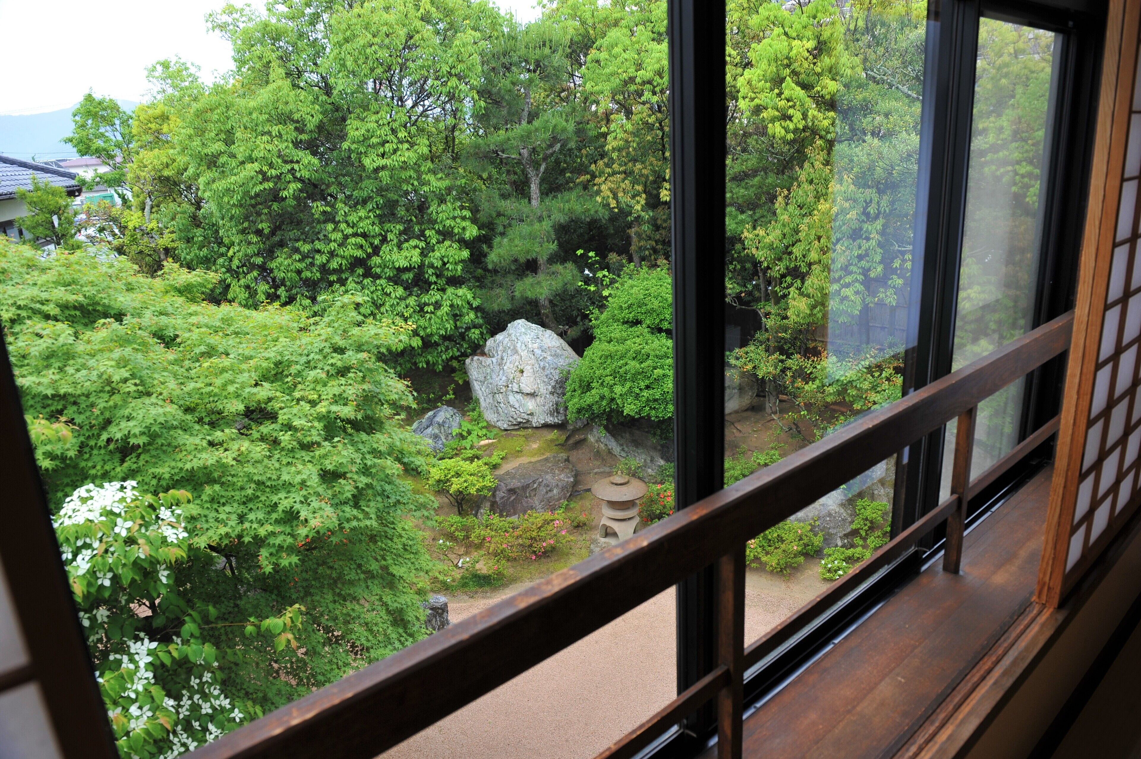 A view of a traditional Japanese garden through a window with wooden frames.
