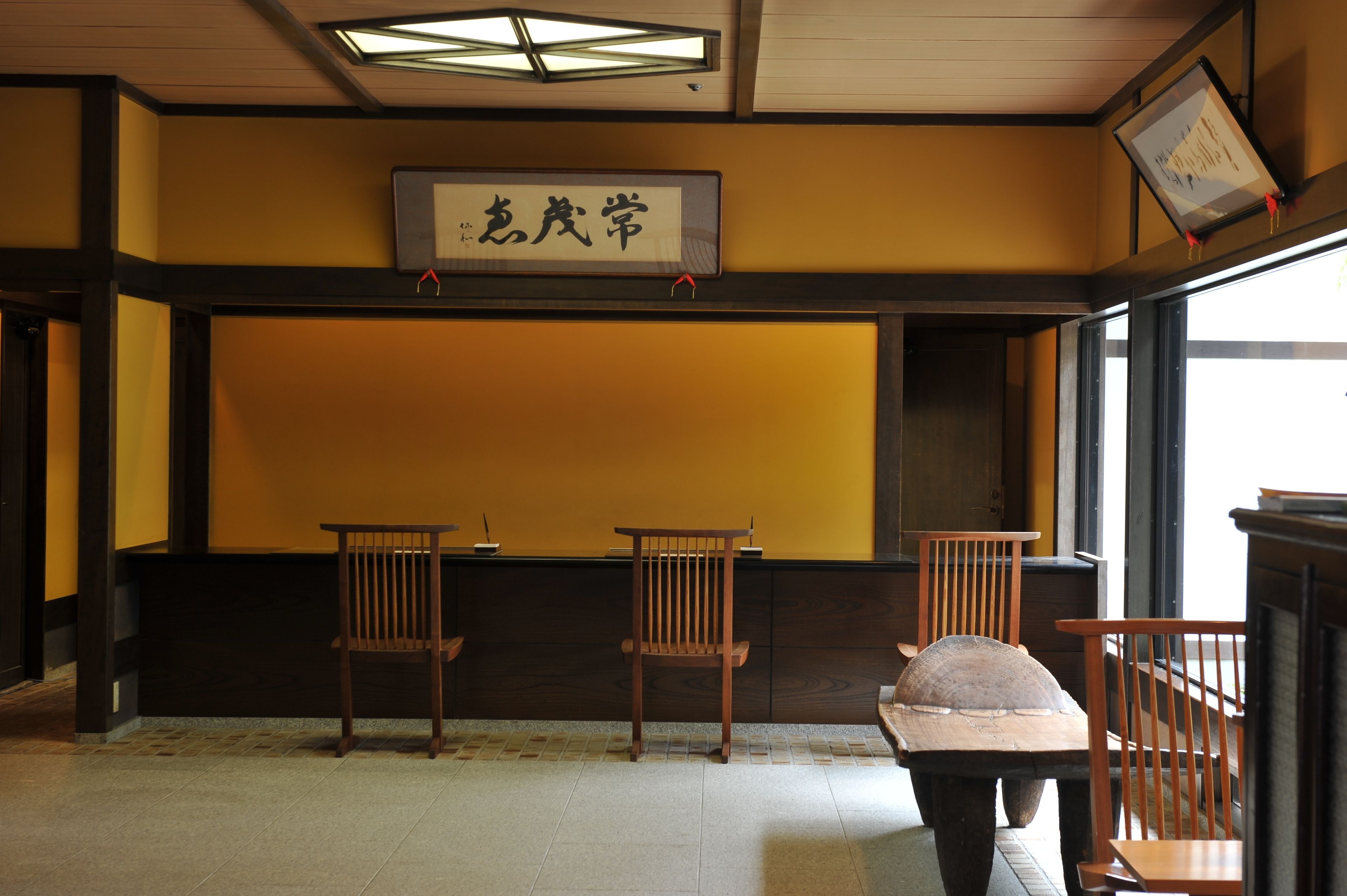 A traditional Japanese room with tatami flooring, a low wooden table, and three wooden chairs.