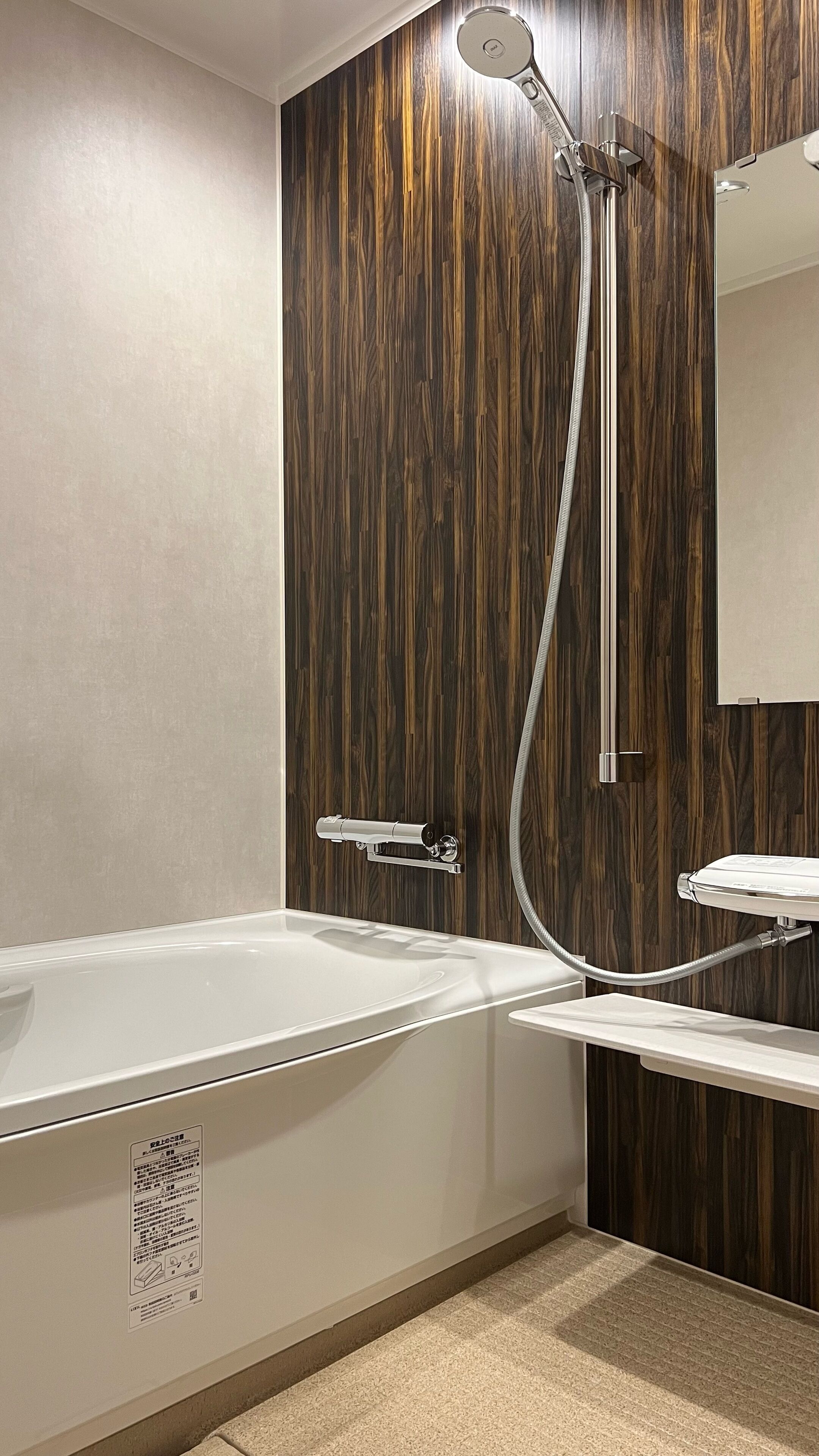A modern bathroom with a wooden wall, a bathtub, a shower, and a sink.