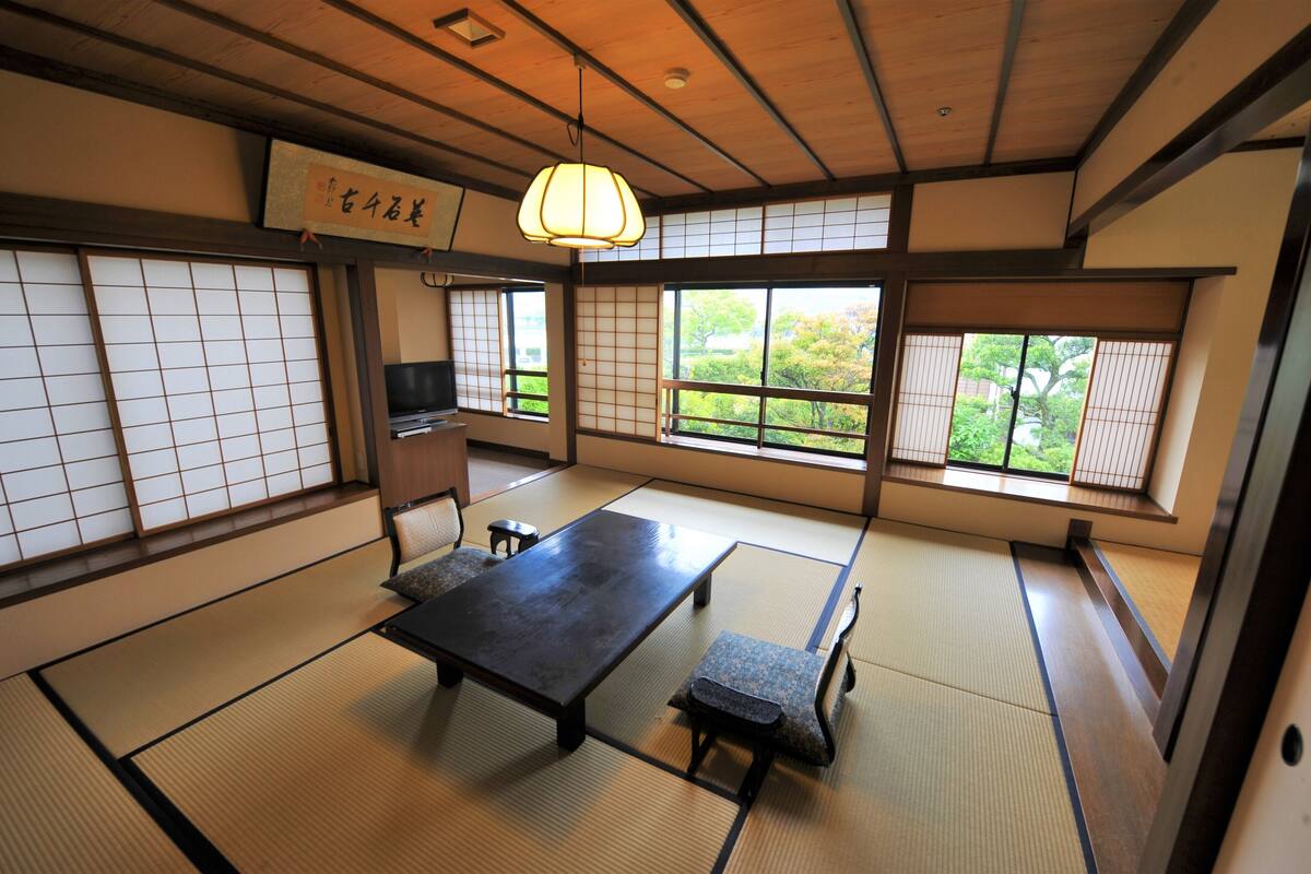 A traditional Japanese room with tatami flooring, a low table, benches, and sliding doors.