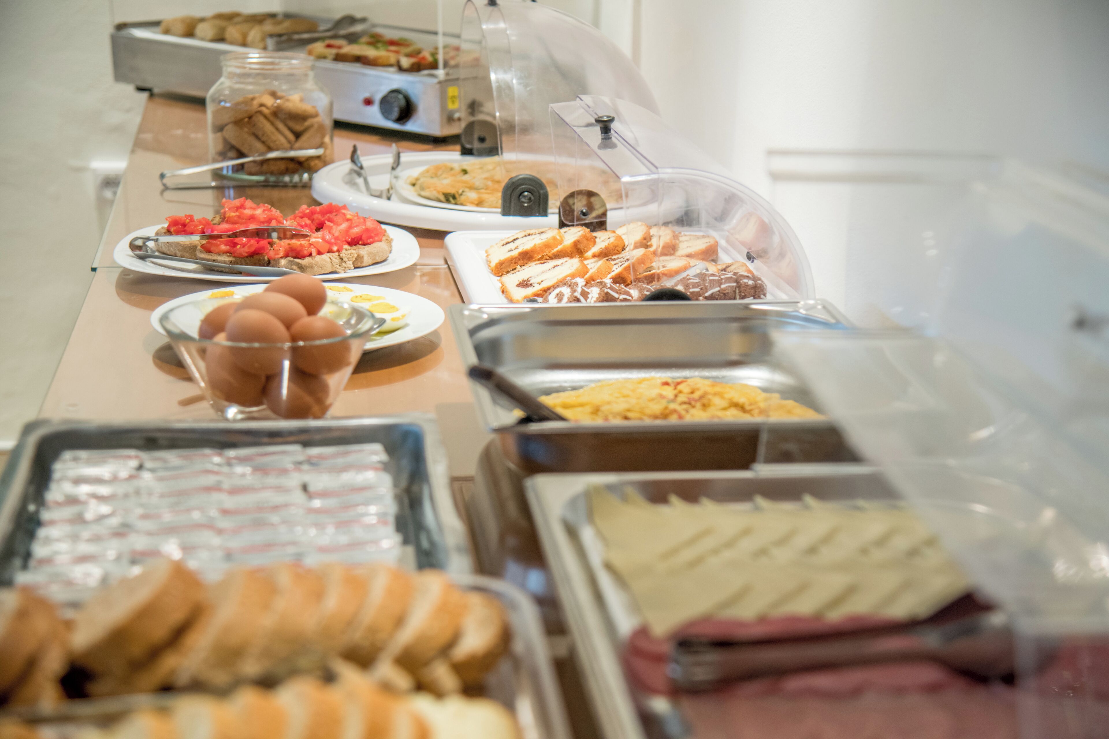 En buffet med forskellige retter, herunder brød, æg og bagværk.