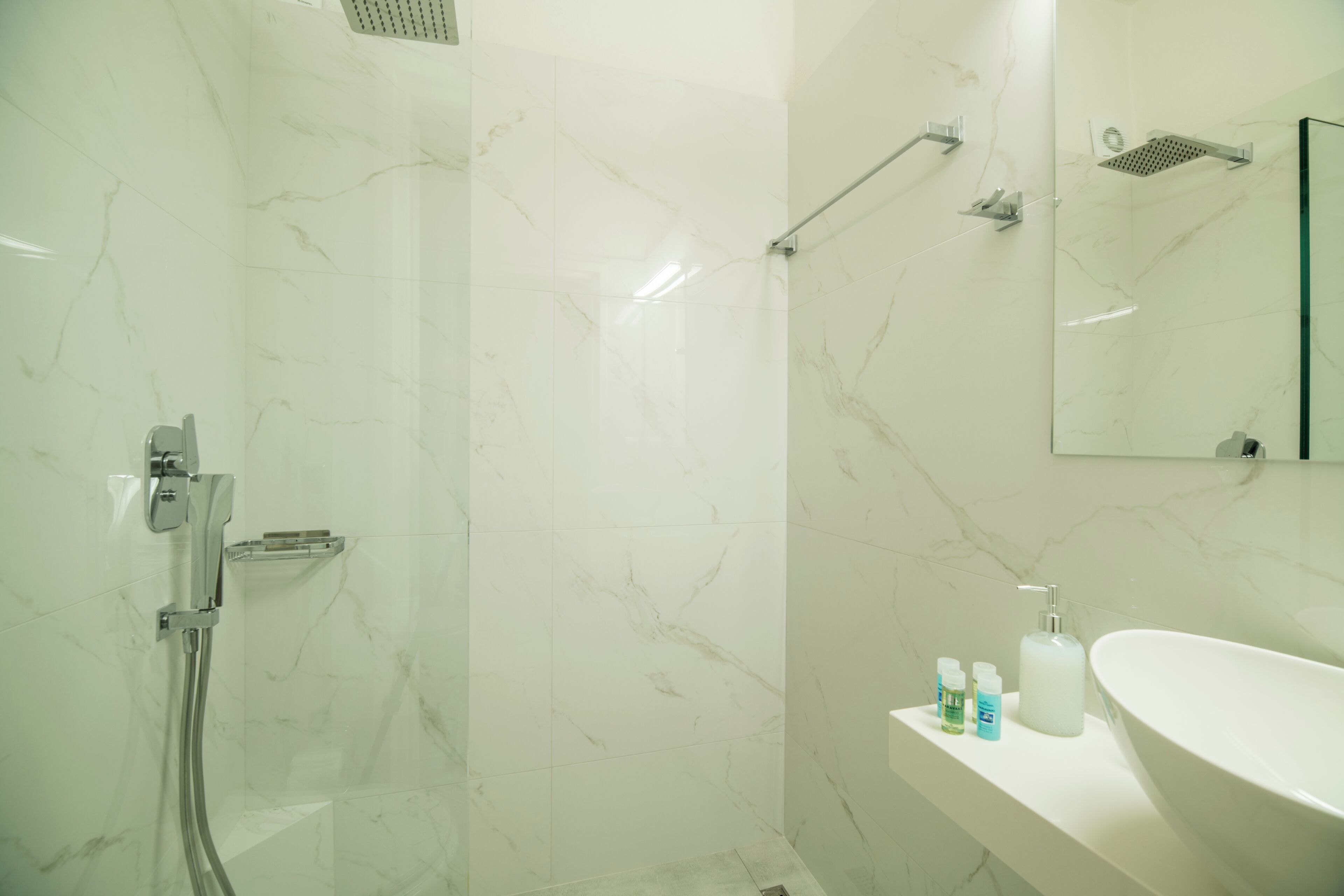 Un baño con ducha, lavamanos y espejo.