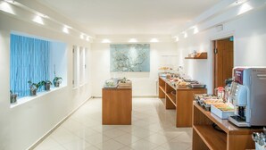 Um lobby de hotel moderno com uma mesa de recepção, uma máquina de café e uma janela grande com plantas.