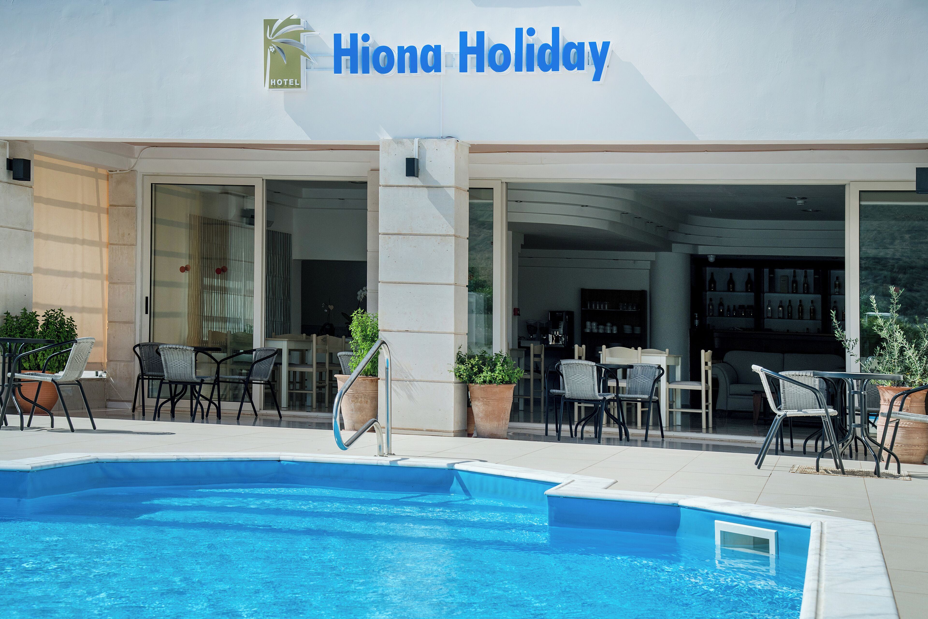 A hotel named Hiona Holiday with a swimming pool, outdoor seating, and a bar area.