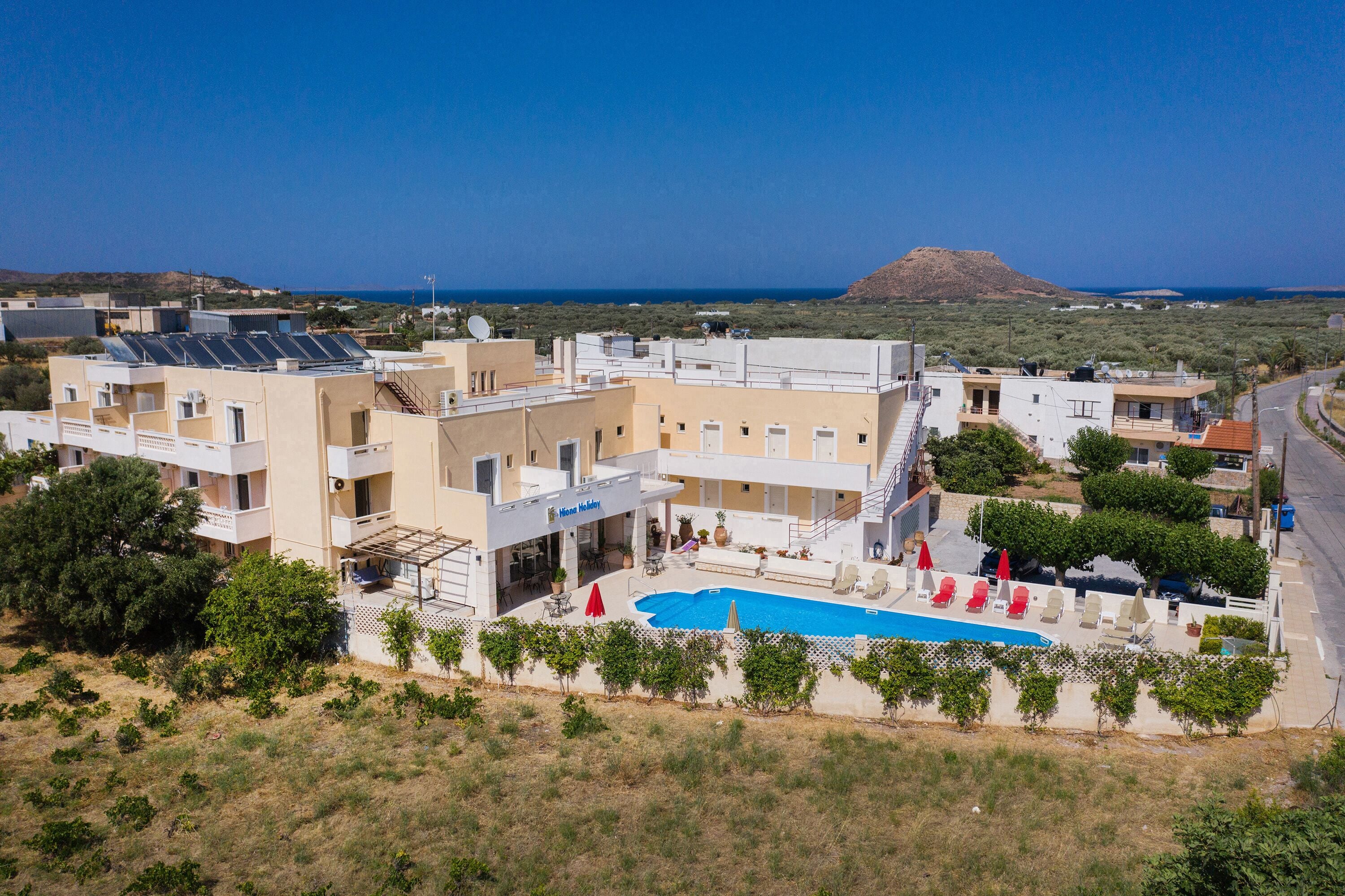 A hotel with a swimming pool, solar panels, and a view of the sea.