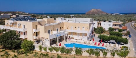Un hotel con piscina, paneles solares y vistas al mar.