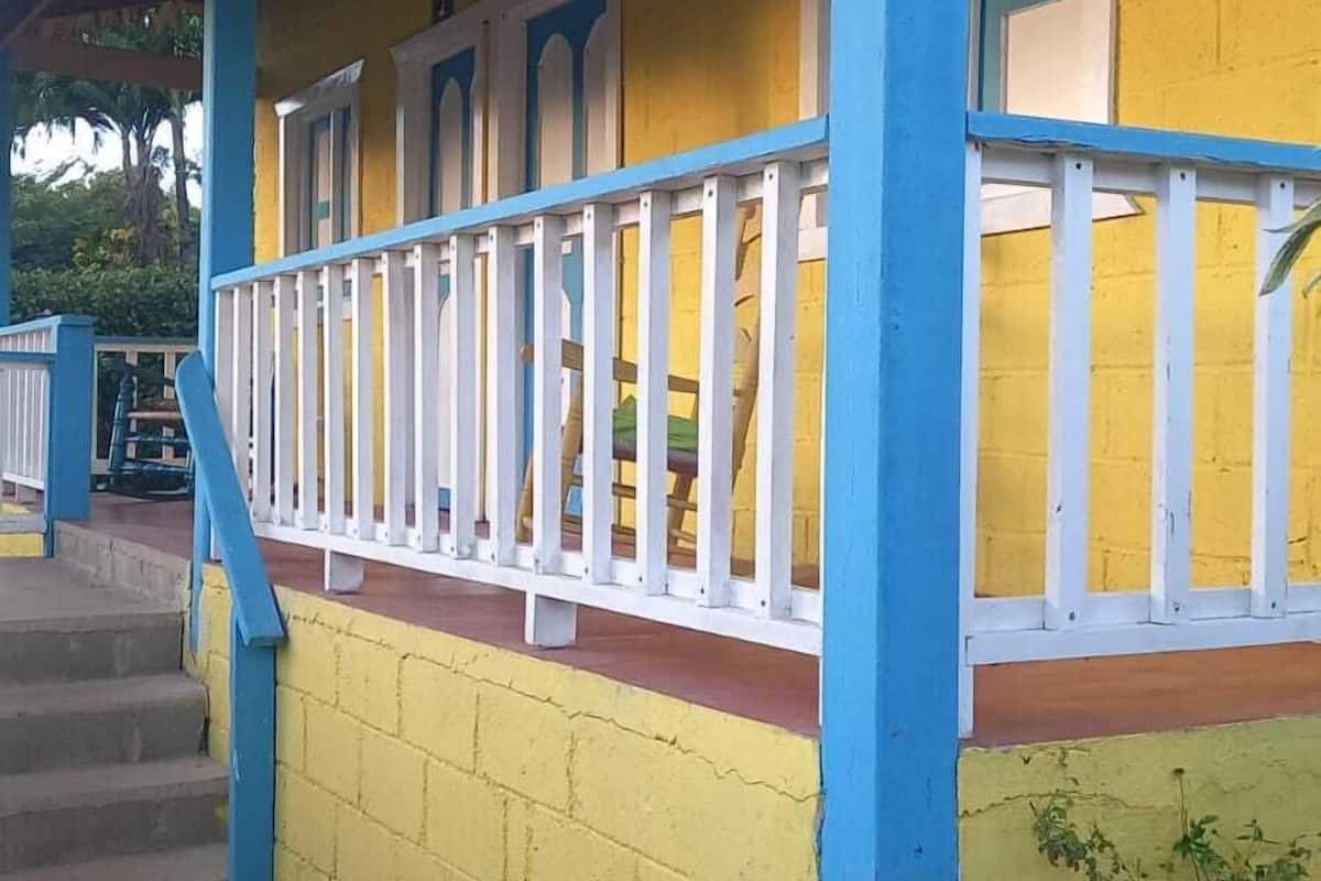 Un bâtiment jaune avec des colonnes bleues et une balustrade blanche.