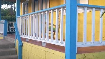 Un bâtiment jaune avec des colonnes bleues et une balustrade blanche.
