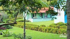 Una casa con techo rojo, rodeada de jardines y setos bien cuidados.