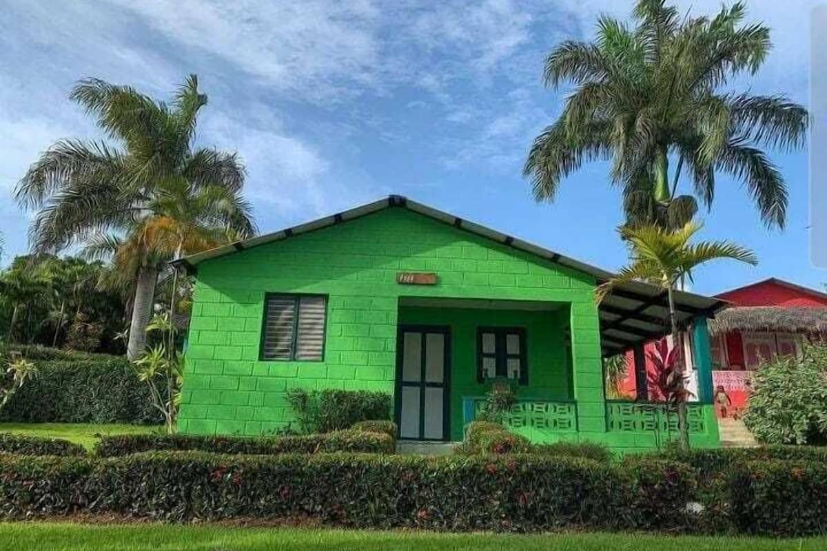 Un petit bâtiment d’un seul étage, à l’extérieur vert, avec une porte noire et des fenêtres à cadre blanc.