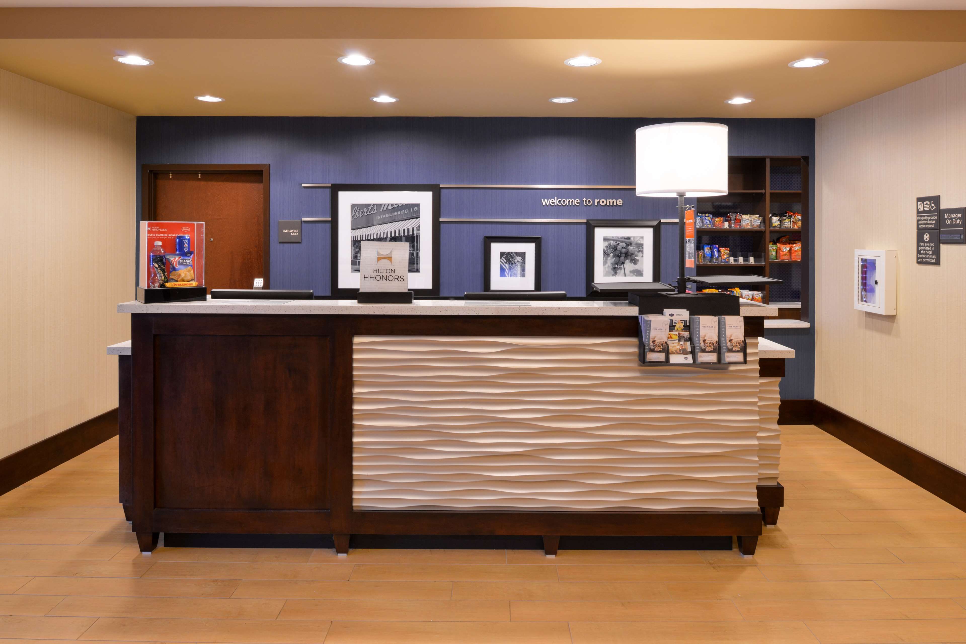 A reception desk with a dark wood finish, a textured white panel, and framed pictures above.