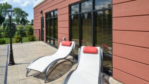 Dos sillones de descanso con cojines rojos en un patio con un edificio rojo al fondo.