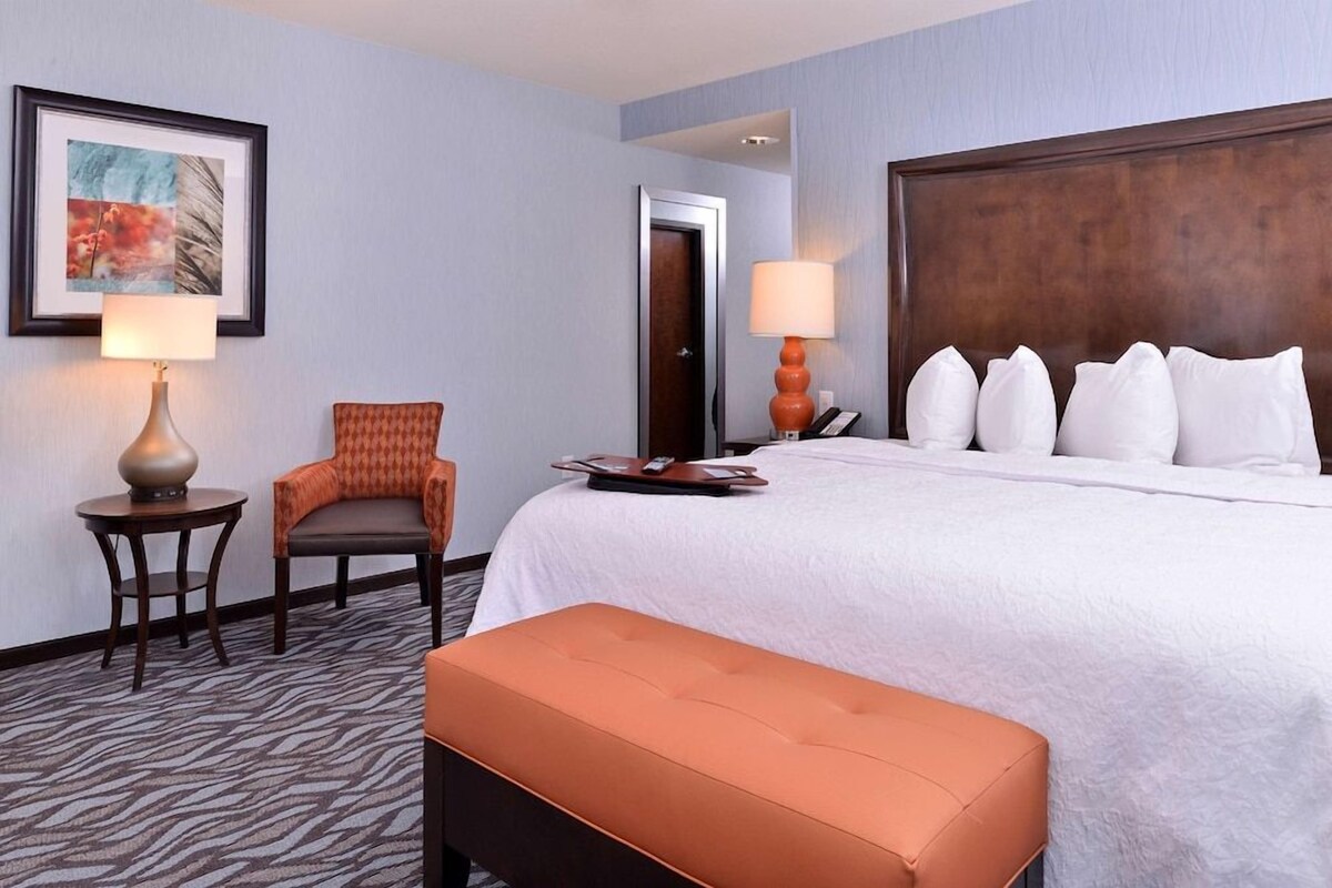 Una habitación de hotel con una cama grande, una silla, una mesa y una lámpara.