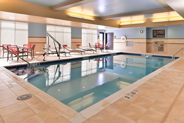 An indoor swimming pool with lounge chairs and a lifeguard station.