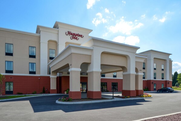 Ein Hampton Inn Hotel mit moderner Fassade, großen Säulen und einem Parkplatz.