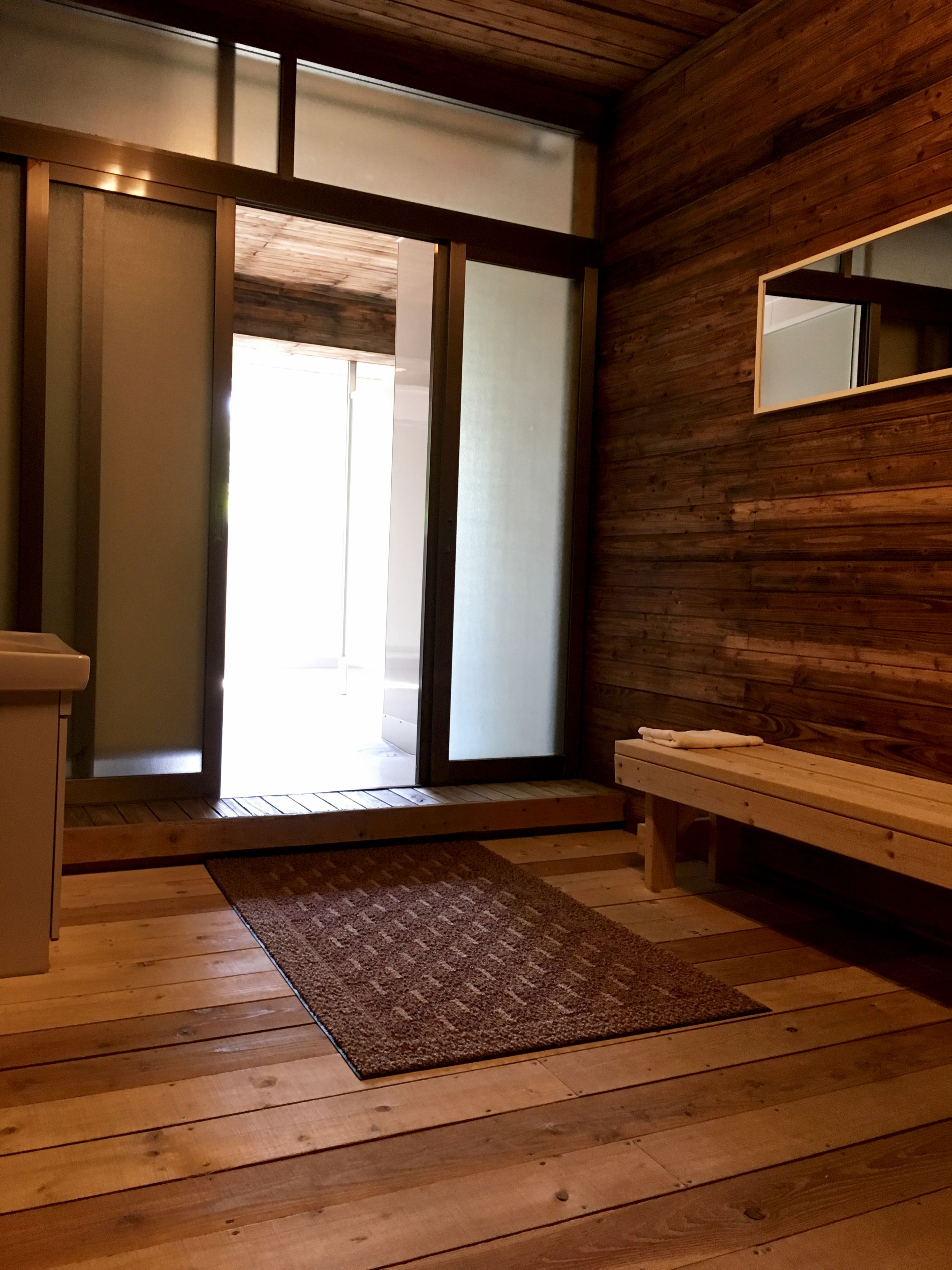 A wooden interior with a sliding glass door leading to a bright outdoor area.