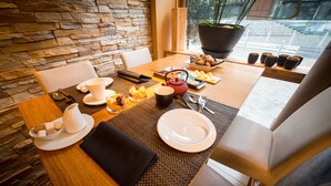A dining table set with plates, cups, and cutlery, with a stone wall and a view of the outdoors. - Hôtel Hors Château (Liege)