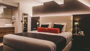 A modern hotel room with a large bed, a bedside table with a lamp, a nightstand with a phone, and a bathroom with a towel rack. - Hôtel Hors Château (Liege)