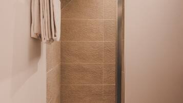 Eine moderne Dusche mit strukturierter Wand, einem Handtuchhalter und minimalistischem Design.