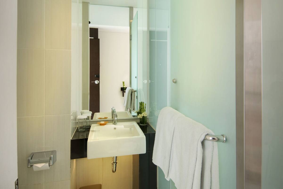 Ein modernes Badezimmer mit einem weißen Waschbecken, einer Toilette und einer Duschkabine aus Glas.